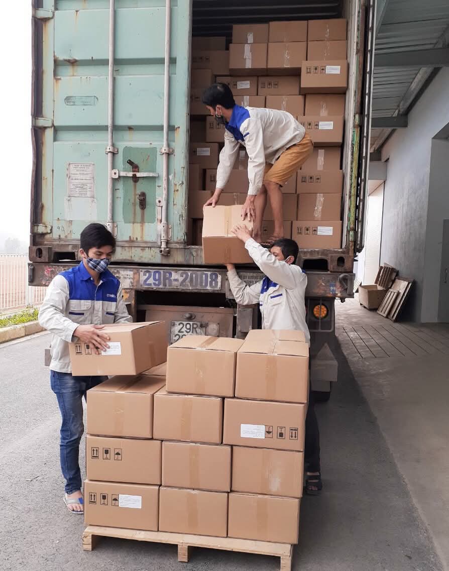 Nhân công chuyển thùng carton từ container xuống pallet gỗ trong kho hàng