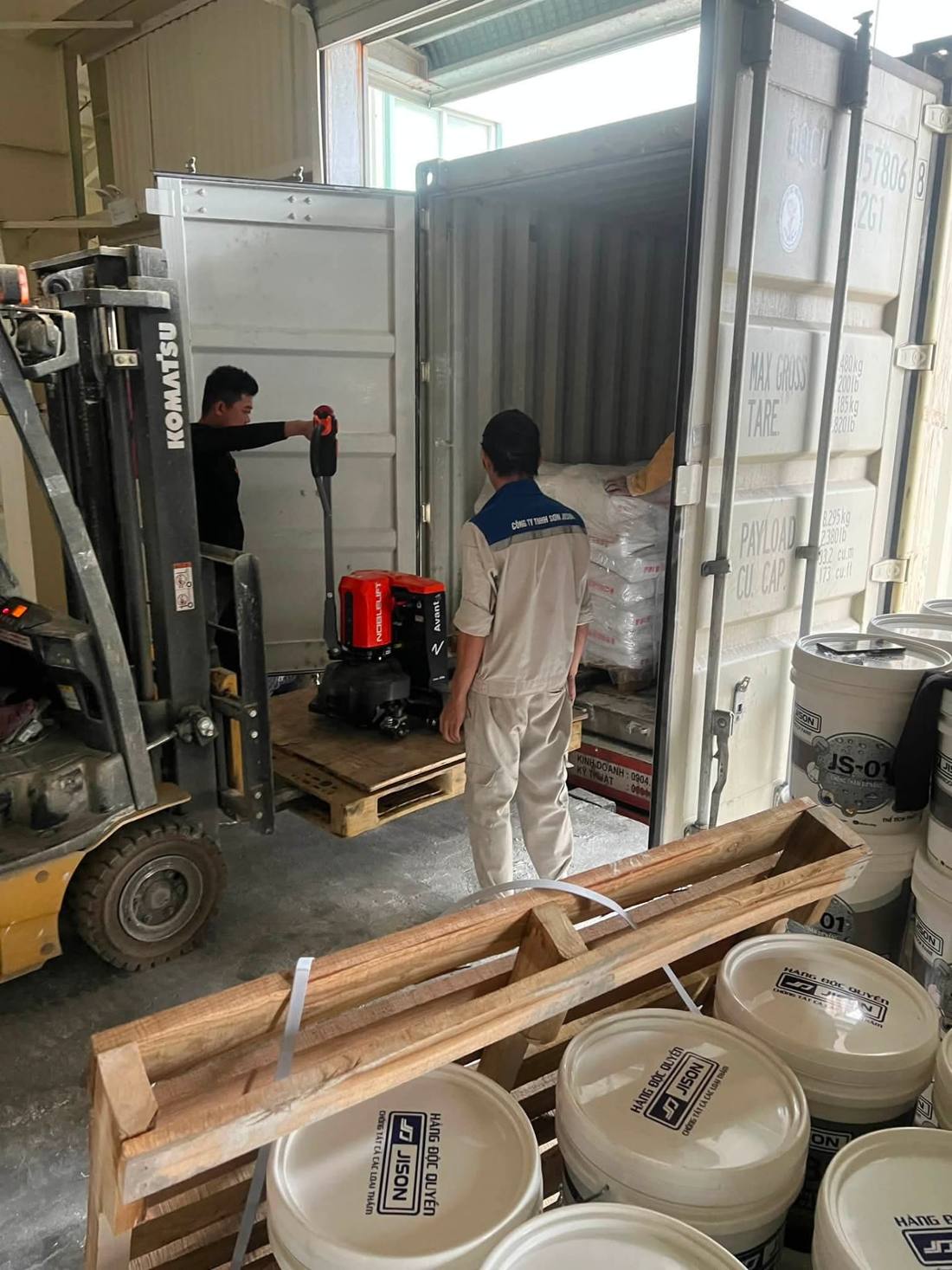 Xe nâng Komatsu và xe nâng tay điện hỗ trợ nhân công xếp hàng cạnh container